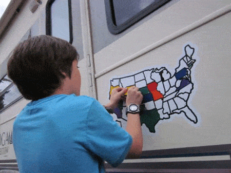 Child happily placing a state sticker onto the map on the family RV